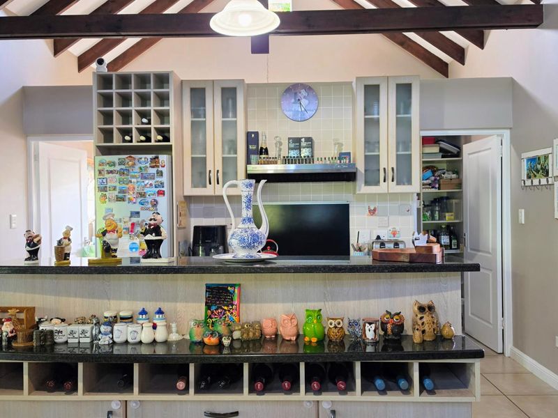 A well-appointed kitchen featuring exposed timber beams, ample built-in cabinetry, a dedicated wine rack, and a functional pantry area.