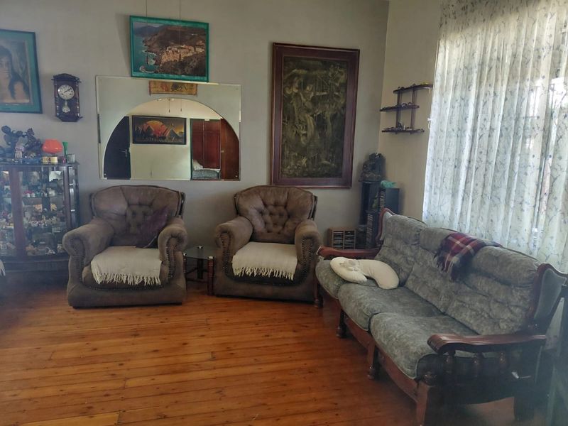 A traditional living room featuring original hardwood flooring and a decorative arch-top wall mirror, offering a classic foundation for modern updates.