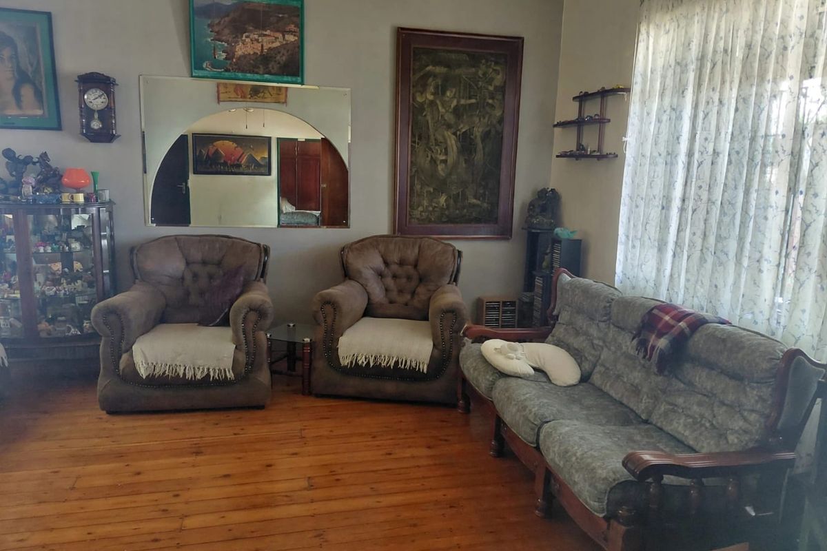 A traditional living room featuring original hardwood flooring and a decorative arch-top wall mirror, offering a classic foundation for modern updates.