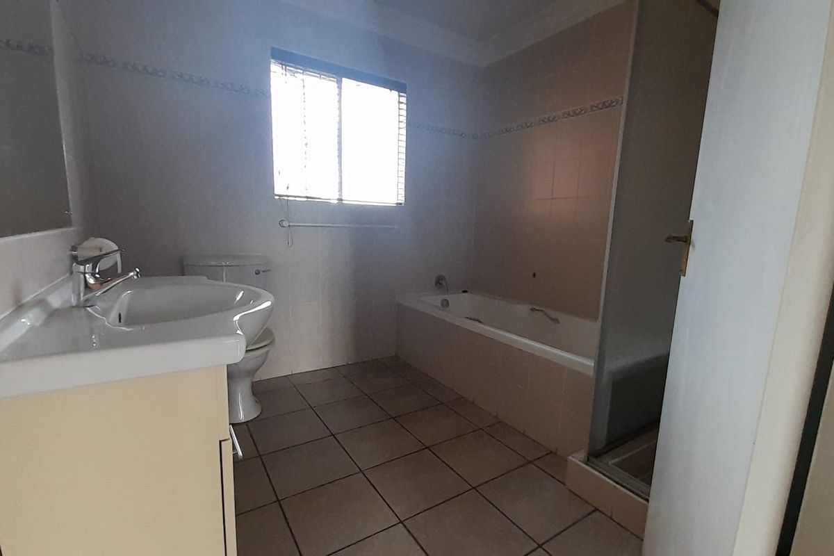 A functional bathroom featuring a vanity basin, a bathtub, and a separate shower enclosure with tiled flooring and walls.