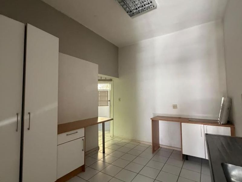A functional kitchen space featuring tiled flooring, built-in cabinetry, and a stainless steel sink, currently vacant and ready for updates.