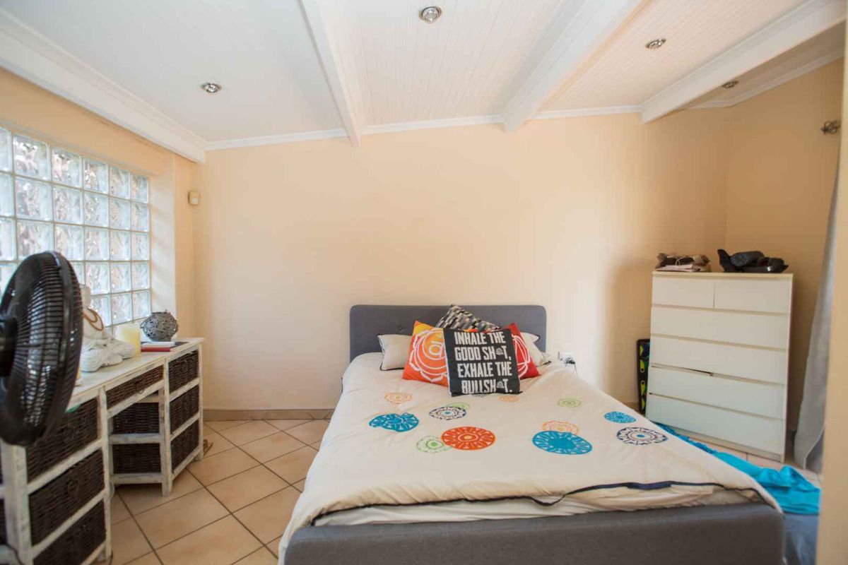 A bedroom featuring tiled flooring, a glass block window, and a white paneled ceiling with recessed lighting.