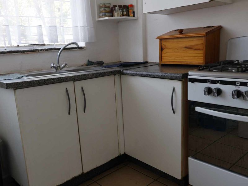 A functional kitchen featuring laminate countertops, a stainless steel double sink, and built-in cabinetry with a gas stove.