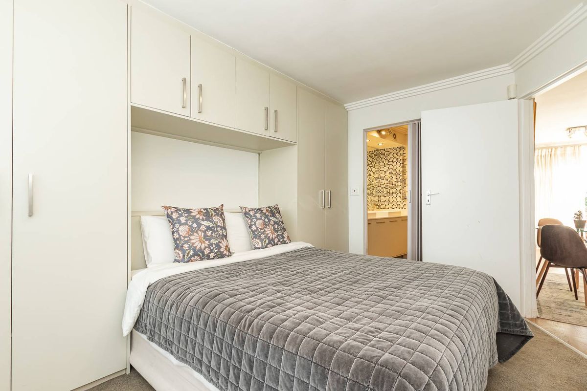 A well-maintained bedroom featuring extensive built-in cabinetry and overhead storage, with direct access to an adjoining bathroom.