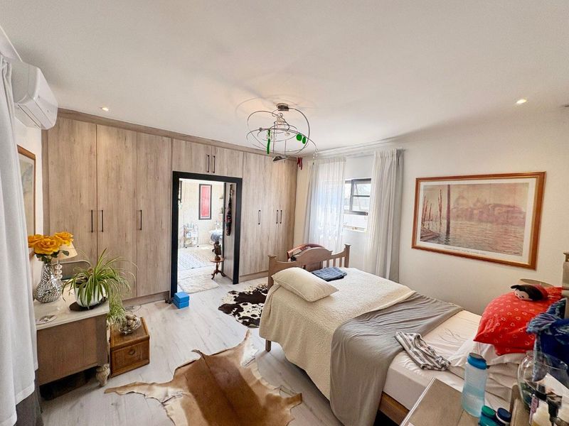Spacious bedroom featuring extensive built-in cabinetry, light-toned laminate flooring, and an integrated air conditioning unit.
