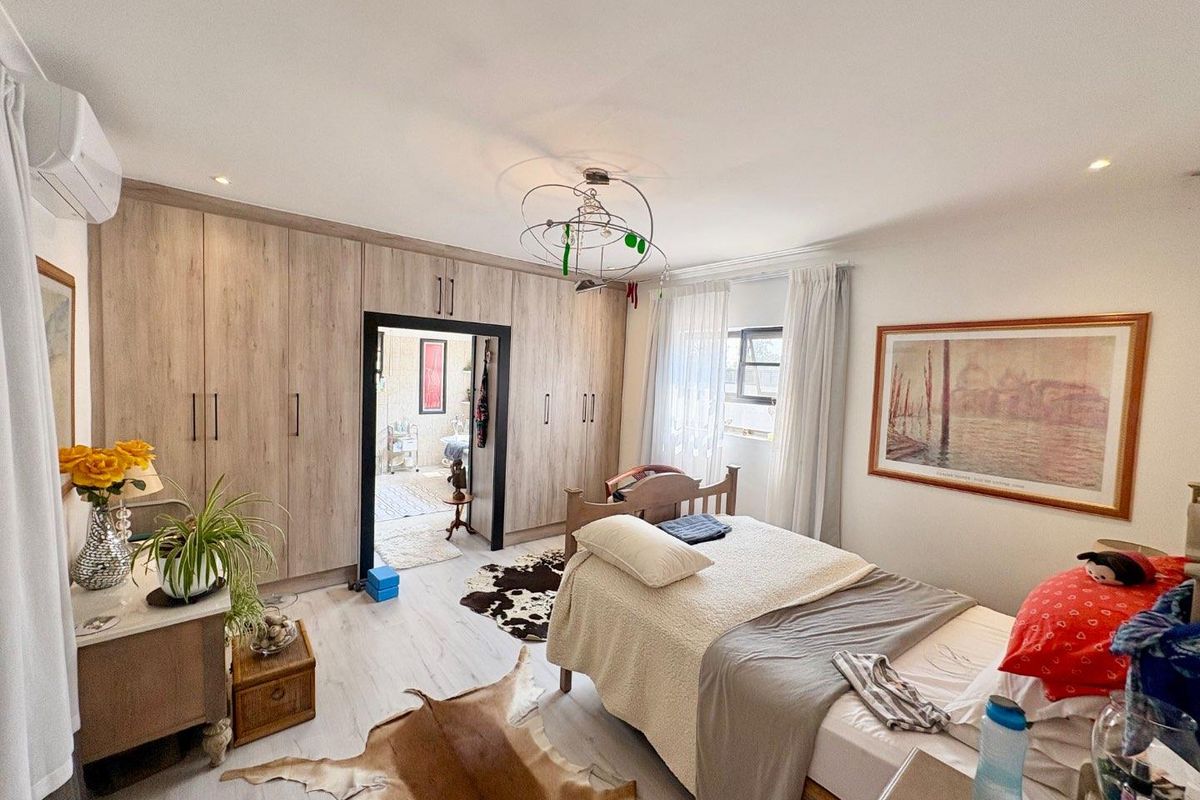Spacious bedroom featuring extensive built-in cabinetry, light-toned laminate flooring, and an integrated air conditioning unit.