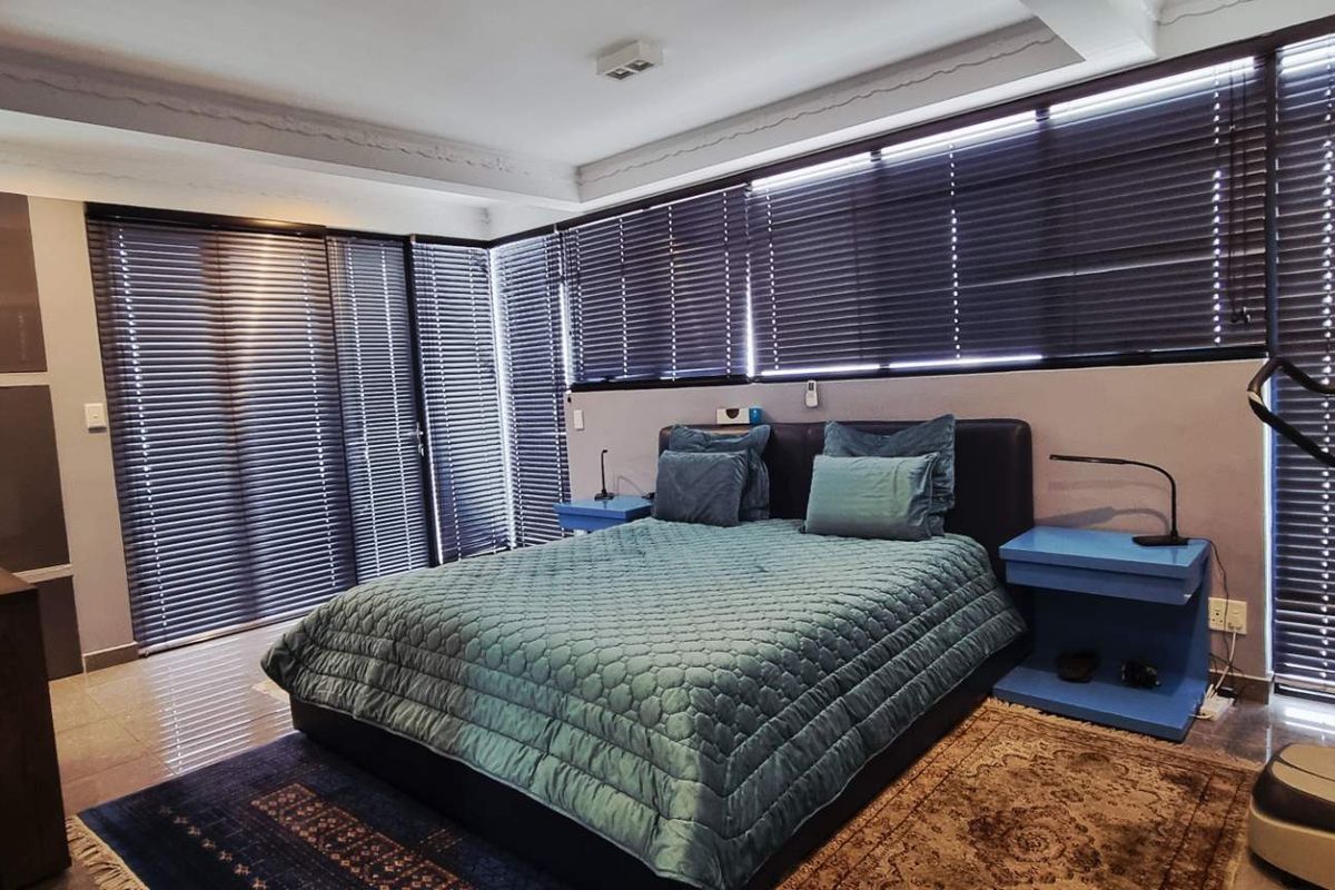 A spacious bedroom featuring large windows with fitted blinds, tiled flooring, and built-in cabinetry.