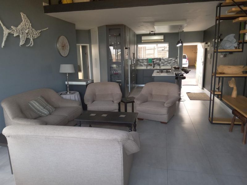 Open-plan living area featuring a modern kitchen with built-in cabinetry, gas hob, and tiled flooring, seamlessly connecting to the lounge space.