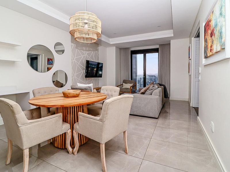 Modern open-plan living and dining area featuring sleek porcelain floor tiles, a recessed ceiling, and direct access to a private balcony.
