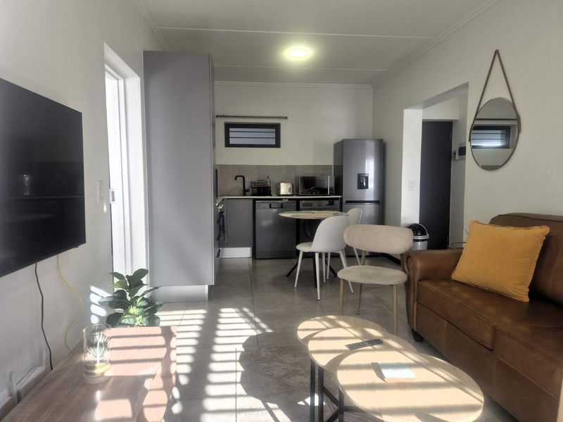 An open-plan living and kitchen area featuring modern grey cabinetry, tiled flooring, and a functional layout suitable for compact apartment living.