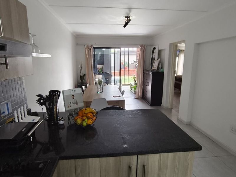 Open-plan living area featuring a modern kitchen with granite countertops, tiled flooring, and a sliding door leading to an outdoor space.