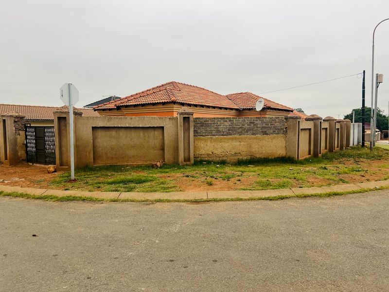 Street view of the property showing the perimeter wall, tiled roof, and gated entrance from the road.
