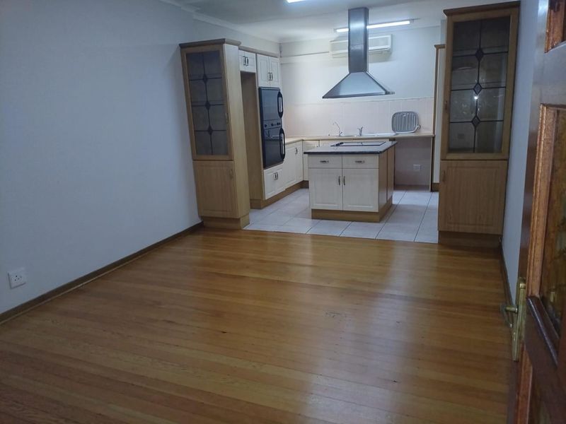 Open plan kitchen and living area featuring timber flooring, tiled kitchen zone, built-in cabinetry, kitchen island, and integrated appliances.