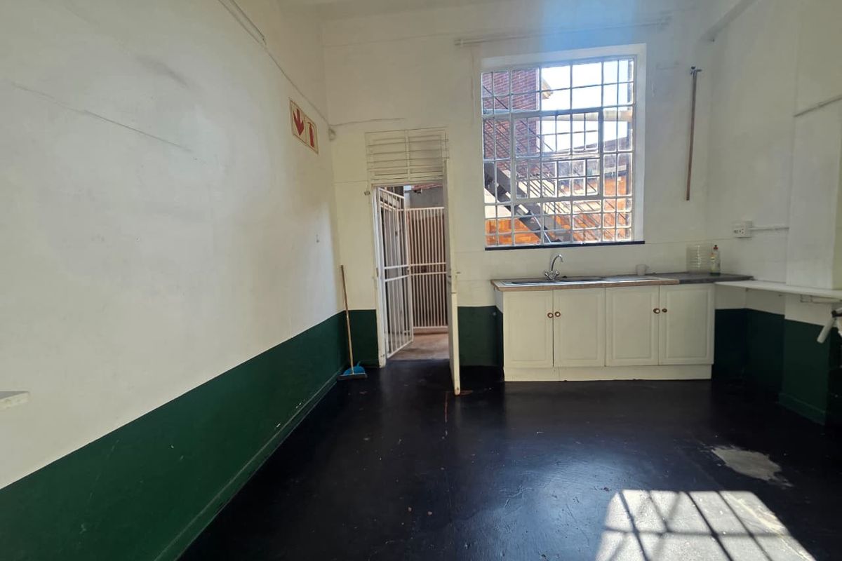 A functional utility or kitchen space featuring built-in cabinetry, a sink, and large industrial-style windows, providing a practical area for business operations.