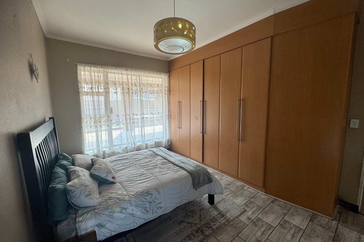 A bedroom featuring extensive built-in wooden cabinetry, tiled flooring, and a large window providing natural light.