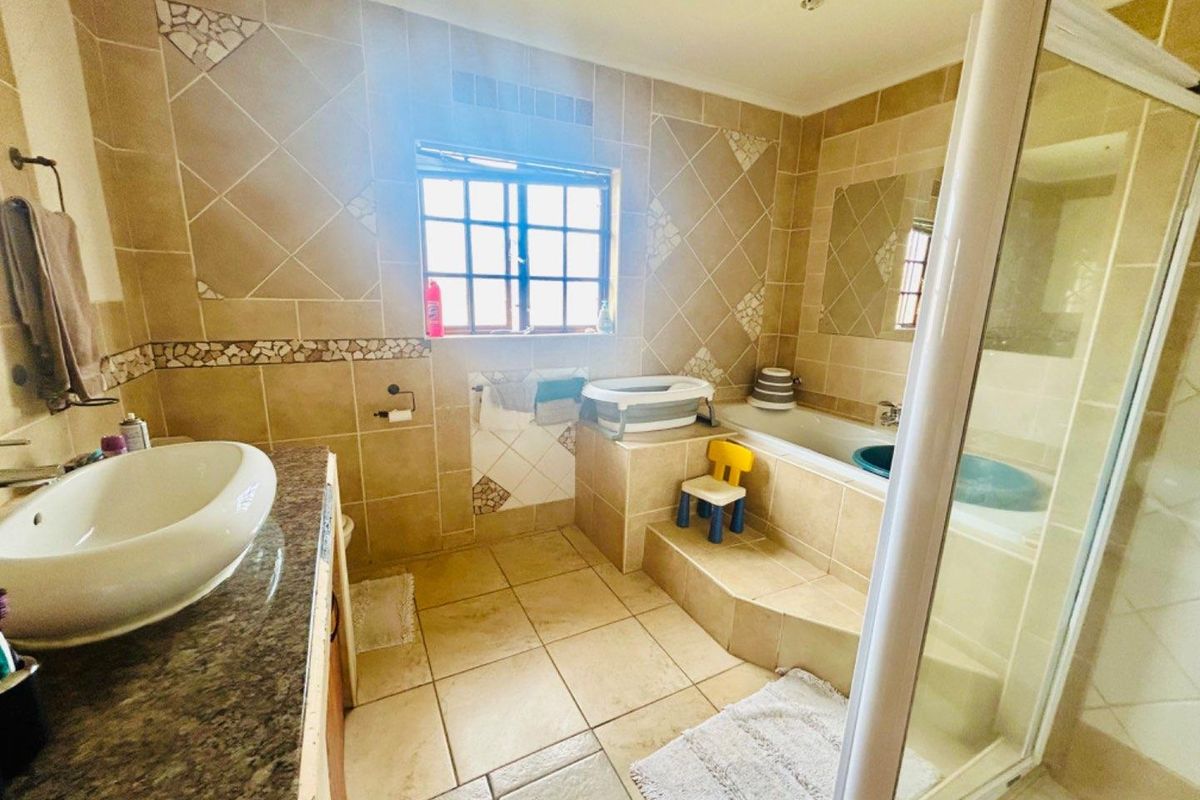 A tiled bathroom featuring a built-in bathtub, a separate glass-enclosed shower, and a vanity basin with granite countertop.