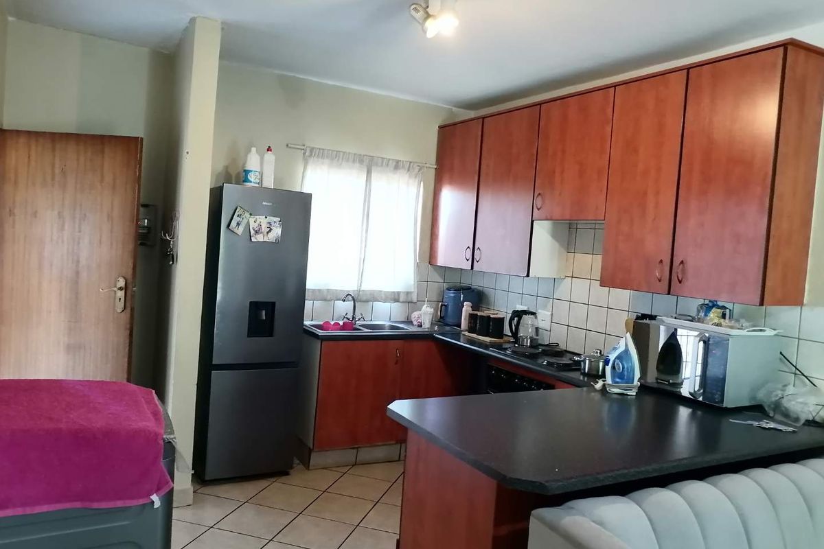 Functional kitchen featuring wood-finish cabinetry, tiled backsplash, and a breakfast bar counter, providing a practical layout for daily meal preparation.
