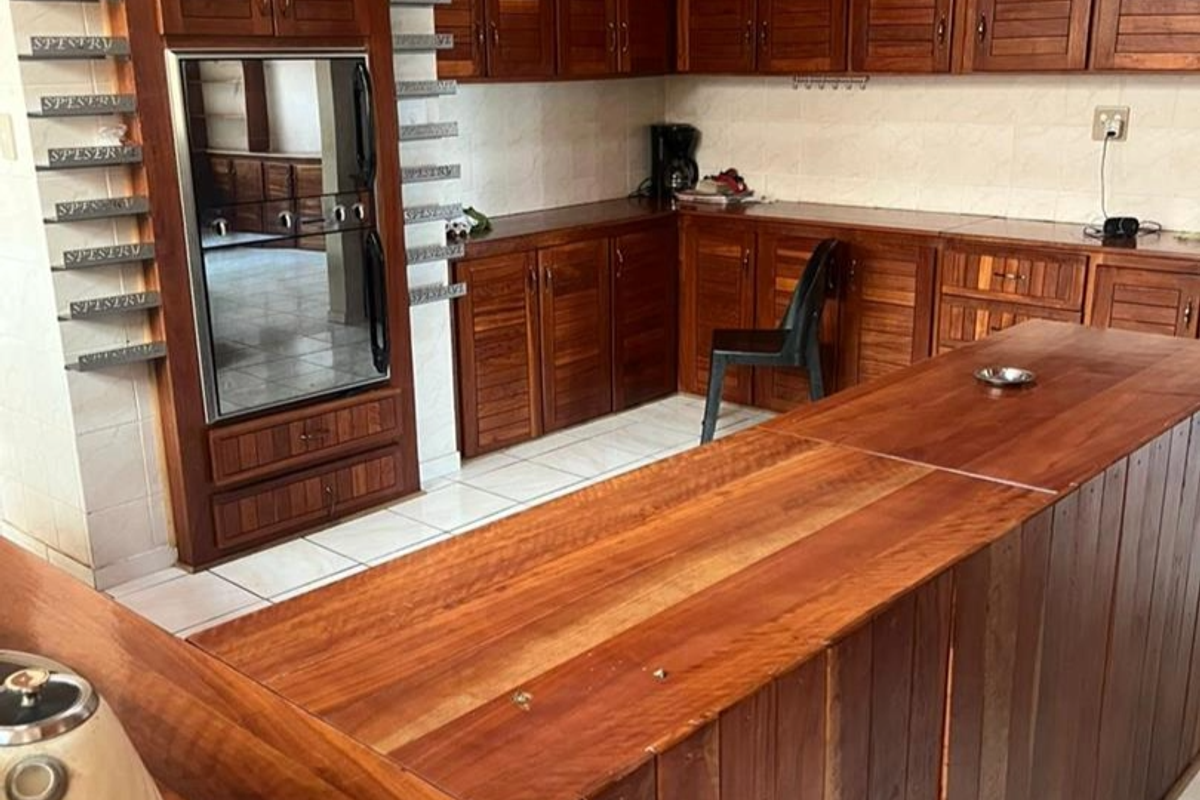 A spacious kitchen featuring extensive custom wooden cabinetry, a large central wooden island, and built-in oven, offering ample storage and workspace.