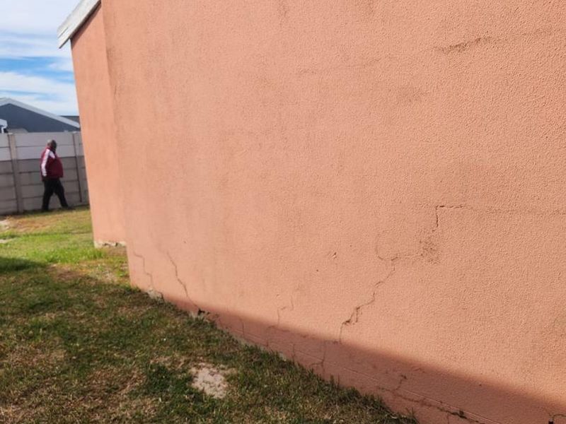 Exterior view of the rear wall showing significant visible cracking in the plaster and masonry structure.