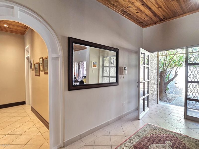 Welcoming entrance hall featuring tiled flooring, a distinctive arched doorway, and a warm timber-paneled ceiling, providing a bright and inviting transition into the home.