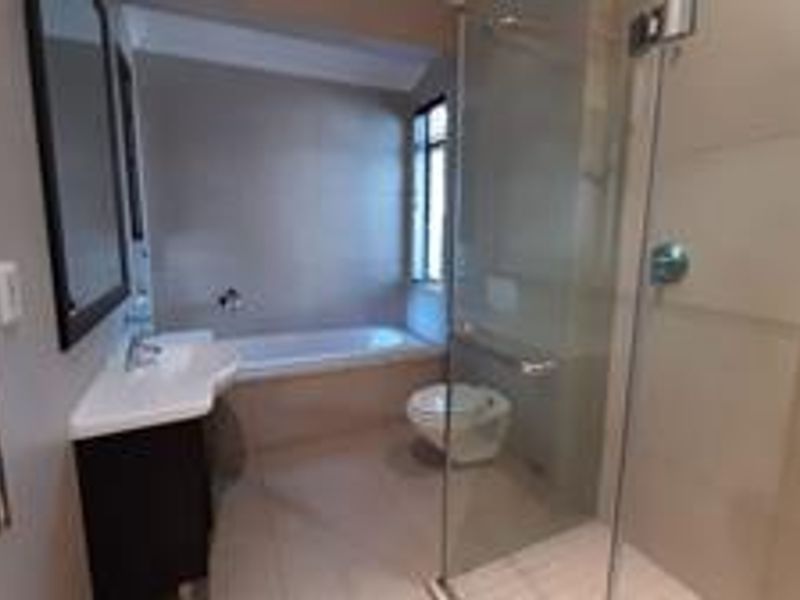 Modern bathroom featuring a glass-enclosed shower, a separate bathtub, a wall-mounted toilet, and a vanity unit with a heated towel rail.