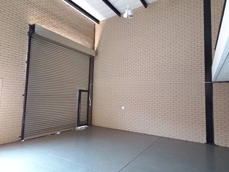 Spacious industrial warehouse unit featuring high ceilings, exposed brick walls, polished concrete flooring, and a large roller shutter door for easy access.