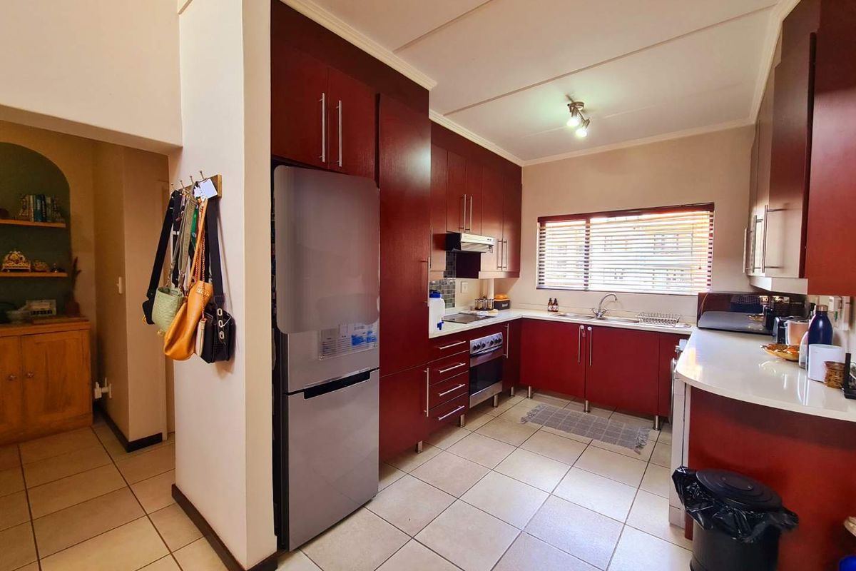 A functional kitchen featuring dark wood cabinetry, tiled flooring, a built-in oven with extractor fan, and a stainless steel sink.