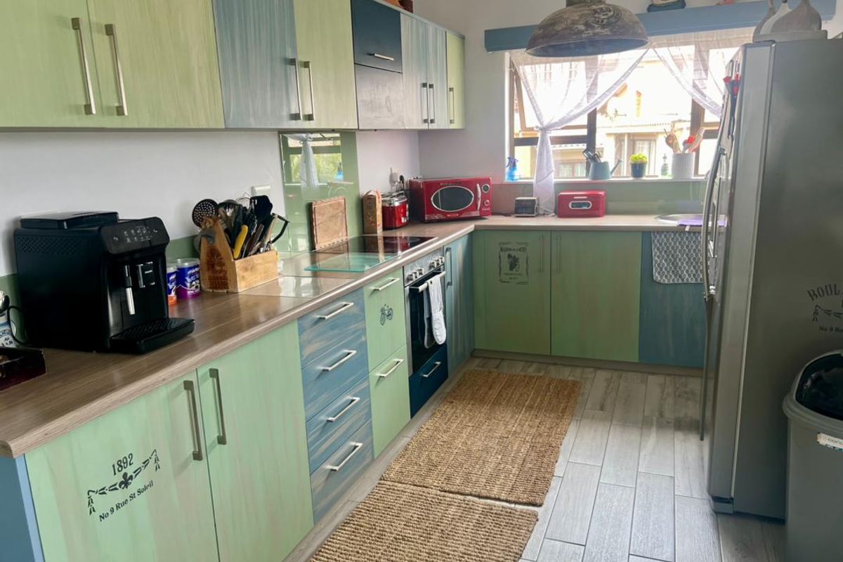 A functional kitchen featuring two-tone cabinetry, wood-look laminate countertops, a built-in oven, and tiled flooring with a window overlooking the exterior.