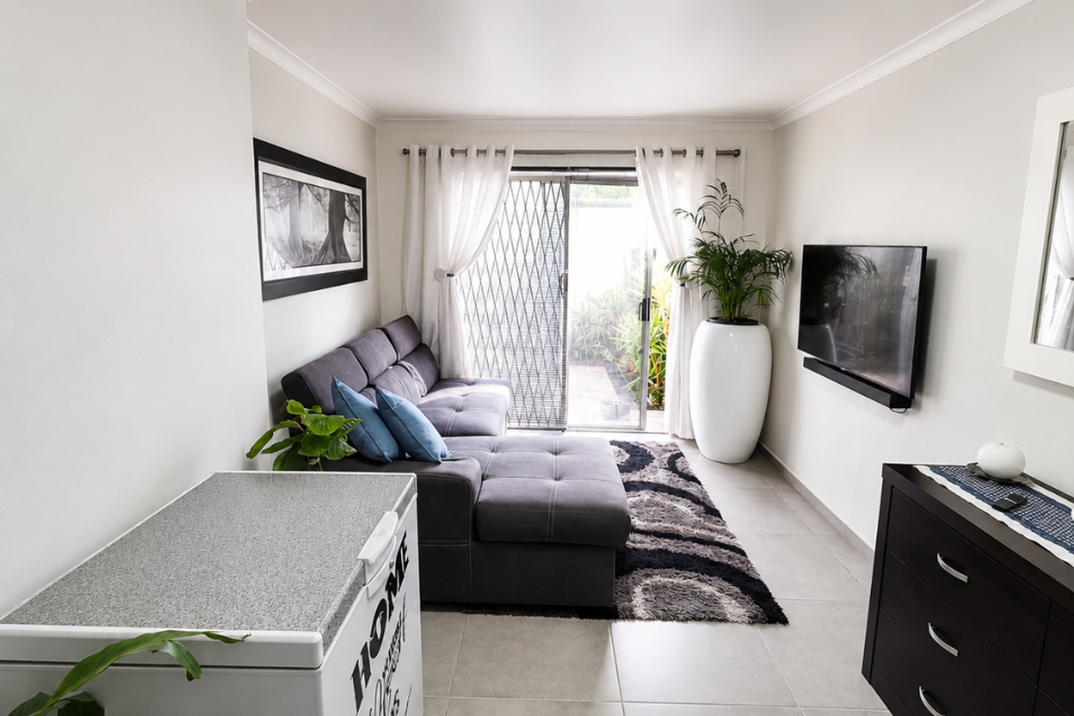 A bright living room featuring large format floor tiles, coving, and a sliding glass door with a security gate leading to an outdoor area.