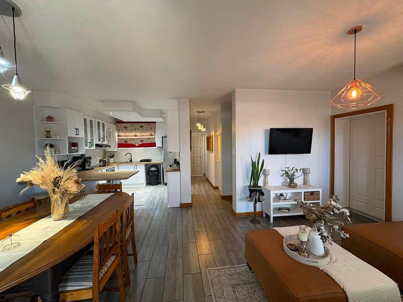 Spacious open-plan living and dining area featuring modern tiled flooring, integrated kitchen cabinetry, and contemporary pendant lighting throughout the main living space.