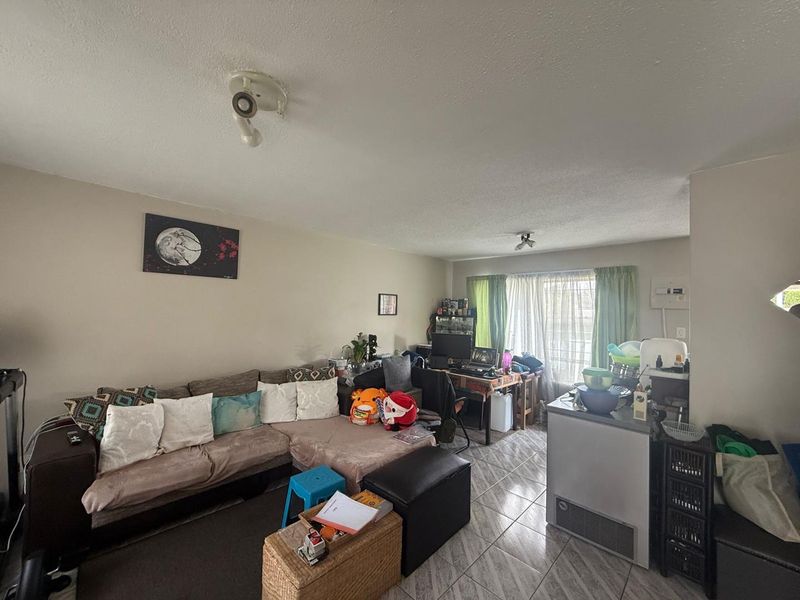 A living room area featuring tiled flooring and ceiling-mounted lighting, providing a functional space for daily living.