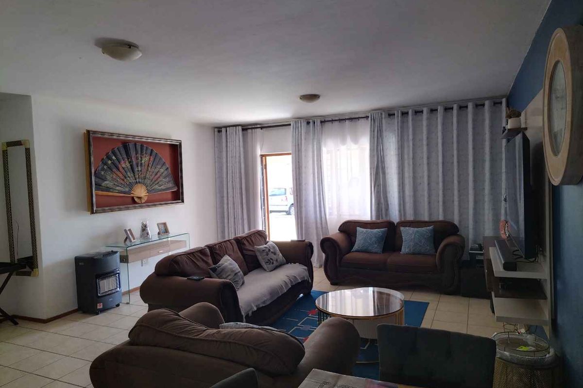 A spacious living room featuring tiled flooring and a sliding glass door providing access to the exterior.