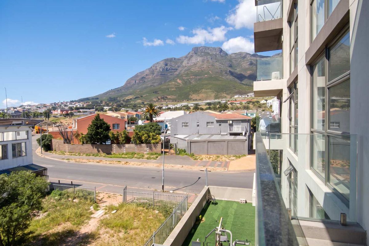 A scenic view from an apartment balcony overlooking the surrounding neighborhood and mountain landscape.