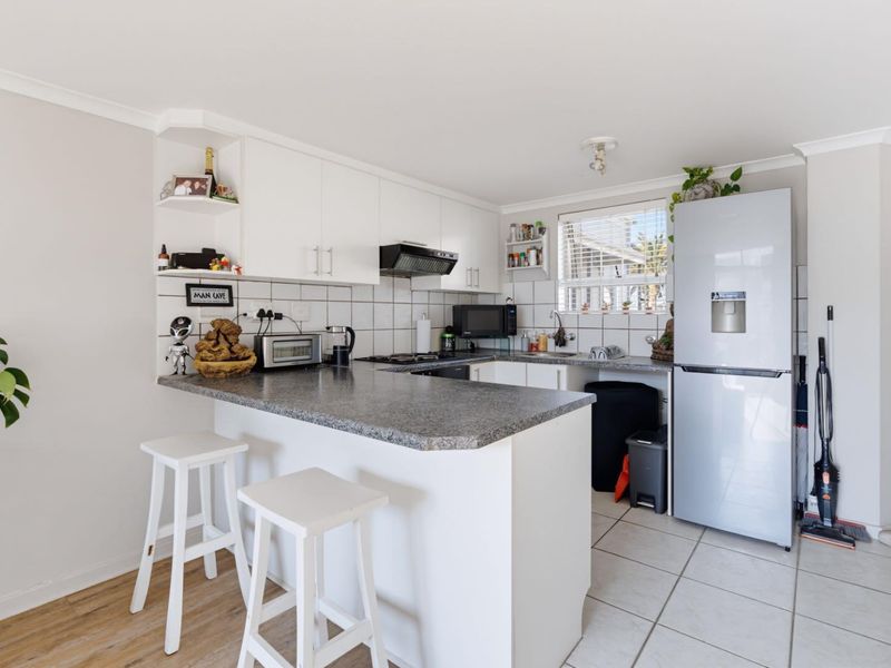 A functional kitchen featuring white cabinetry, granite countertops, a tiled backsplash, and integrated cooking appliances, offering a clean and practical layout.