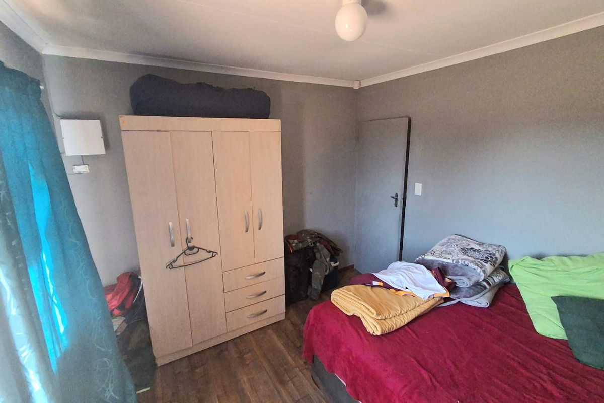 A standard bedroom featuring laminate flooring and neutral wall finishes, providing a functional space for rest.