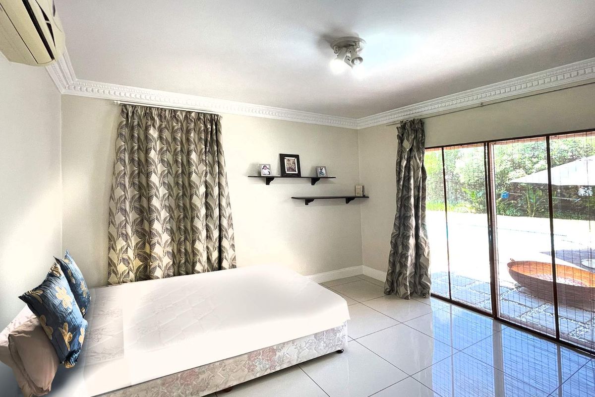A bright bedroom featuring tiled flooring, decorative ceiling cornicing, and large sliding glass doors providing direct access to the outdoor area.