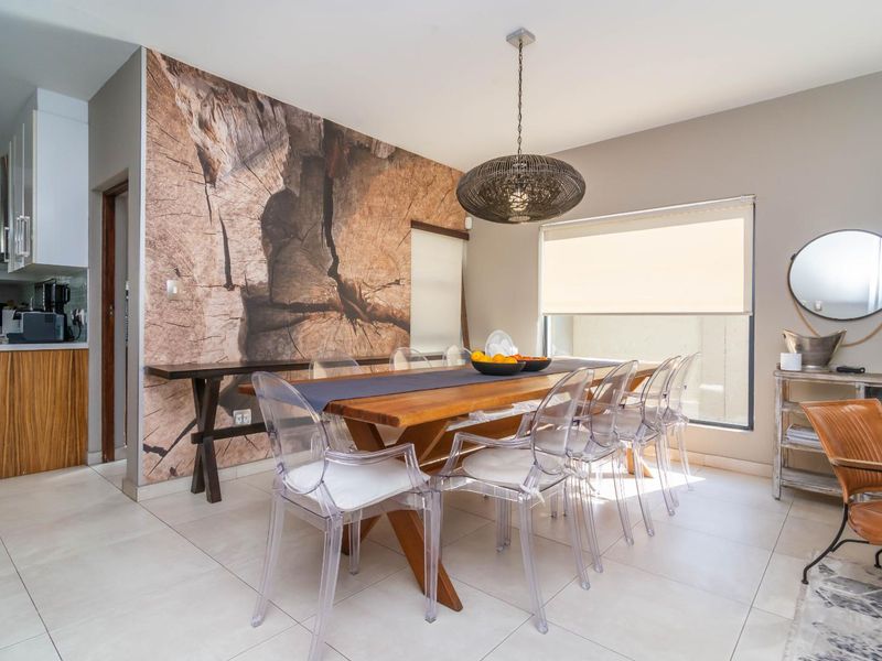 Open-plan dining area featuring tiled floors, a striking wood-grain feature wall, and seamless flow into the adjacent modern kitchen.