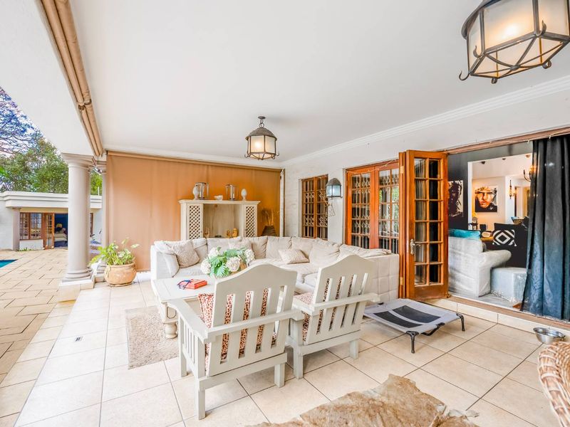 A spacious covered patio featuring tiled flooring, decorative columns, and folding glass doors that provide seamless access to the interior living area.