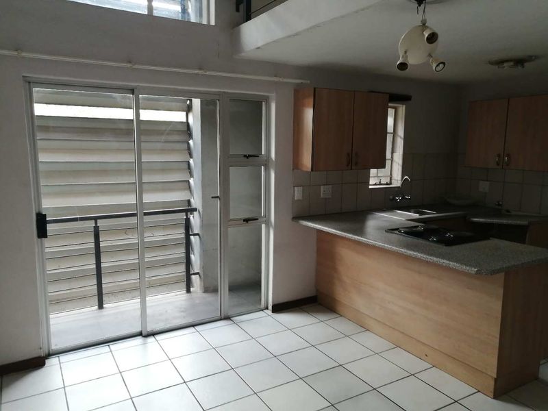 Open plan kitchen and living area featuring tiled floors, built-in cabinetry, and a sliding glass door leading to a private balcony.