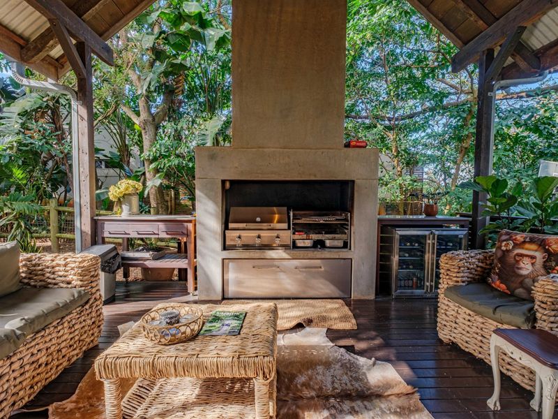 Covered outdoor patio featuring a large built-in braai, timber decking, and a timber roof structure, perfect for alfresco dining and entertaining.