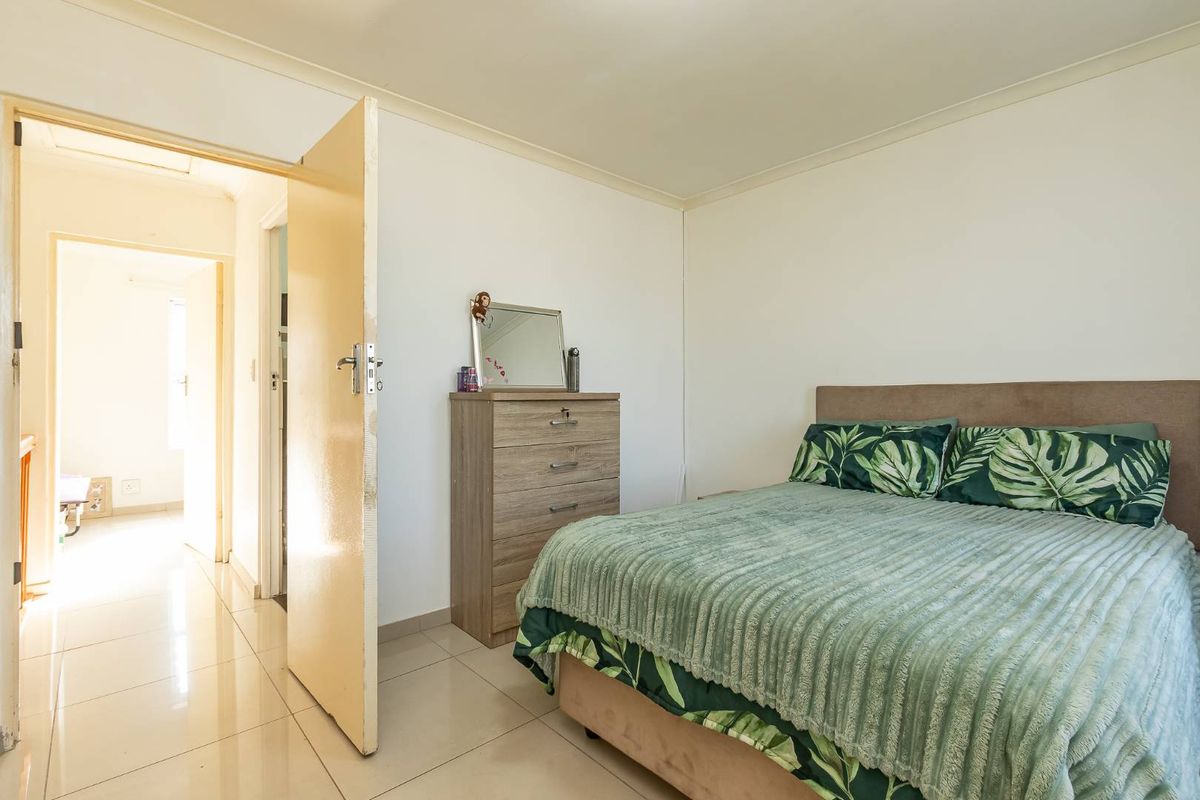 A functional bedroom featuring tiled flooring and neutral wall finishes, providing a clean and simple space for rest.