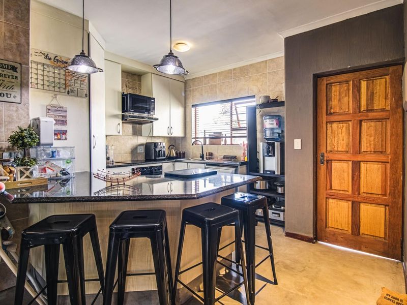 A functional kitchen featuring granite countertops, built-in cabinetry, a tiled backsplash, and a breakfast bar area with pendant lighting.