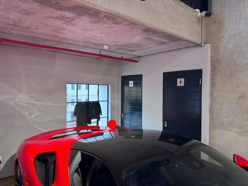 Utility area featuring exposed concrete ceilings, industrial-style steel-framed windows, and access to dedicated restroom facilities within a modern commercial space.
