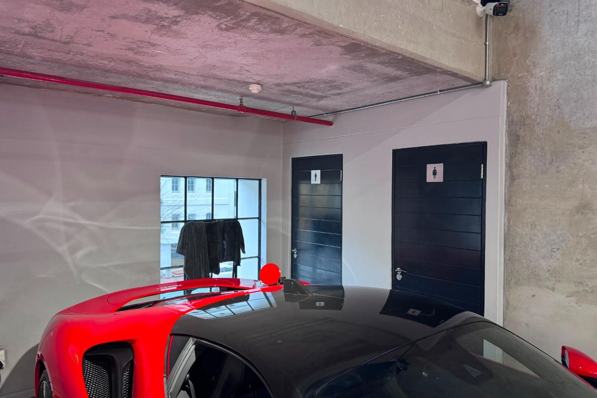 Utility area featuring exposed concrete ceilings, industrial-style steel-framed windows, and access to dedicated restroom facilities within a modern commercial space.