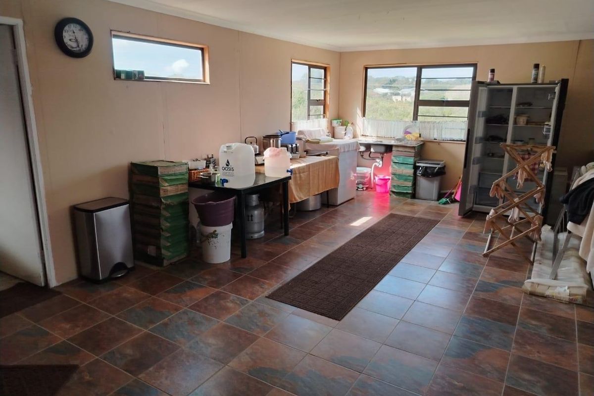 A functional kitchen area featuring tiled flooring, a stainless steel sink, and large windows providing natural light.
