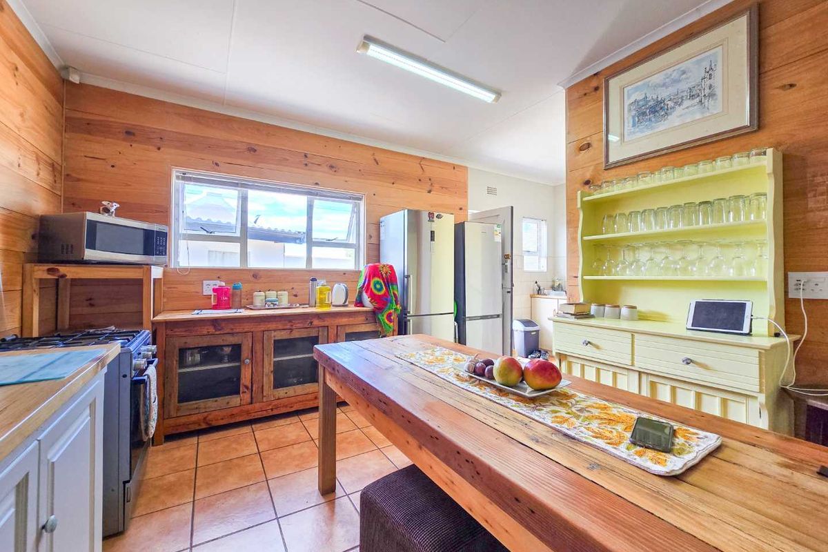 Rustic kitchen featuring timber wall paneling, tiled flooring, a freestanding stove, and built-in cabinetry with a central wooden dining table.