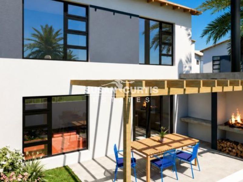 Rear exterior view of a modern townhouse featuring a covered timber pergola, built-in fireplace, and a private patio area.