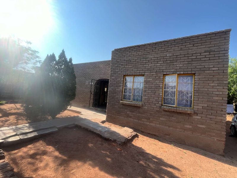 Front exterior view of a face brick house featuring security bars on windows and a paved entrance walkway.