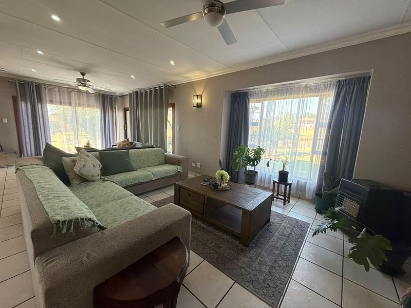 Spacious living room featuring tiled flooring, recessed lighting, ceiling fans, and a large bay window with a built-in fireplace.