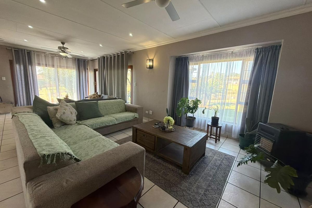 Spacious living room featuring tiled flooring, recessed lighting, ceiling fans, and a large bay window with a built-in fireplace.